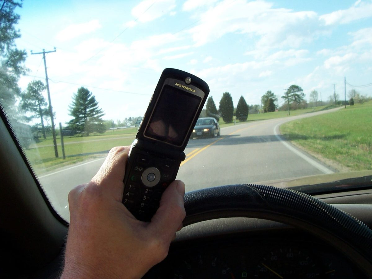 A driver holds a cell phone behind the wheel (file photo).